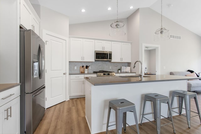 1519 Eagle Shore Ct, Hudsonville, MI 49426 - kitchen featuring stainless steel appliances, a breakfast bar, backsplash, light wood-style floors, and white cabinetry