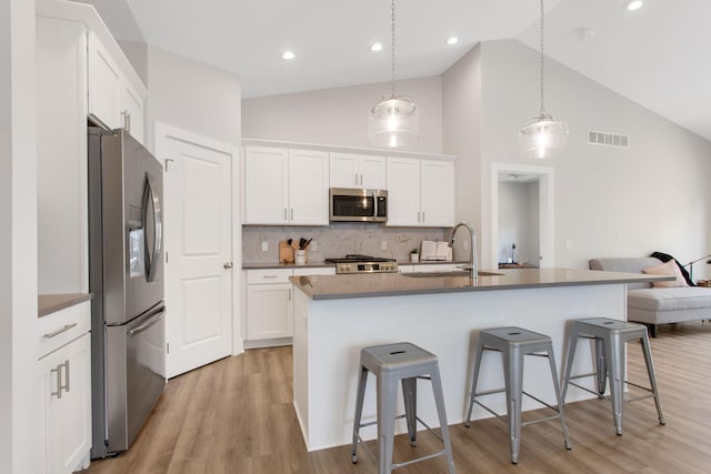 1519 Eagle Shore Ct, Hudsonville, MI 49426 - kitchen featuring appliances with stainless steel finishes, a kitchen bar, high vaulted ceiling, light wood-style floors, and white cabinetry