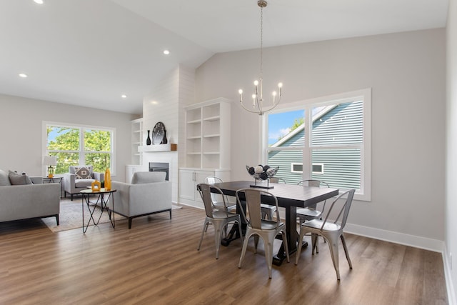 1519 Eagle Shore Ct, Hudsonville, MI 49426 - dining space featuring a chandelier, a large fireplace, wood finished floors, built in features, and high vaulted ceiling