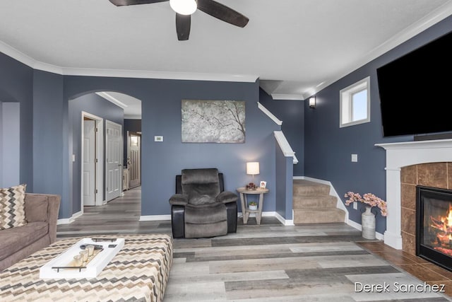 5845 Nile Dr SW, Wyoming, MI 49418 - living room with a tiled fireplace, stairs, wood finished floors, crown molding, and ceiling fan