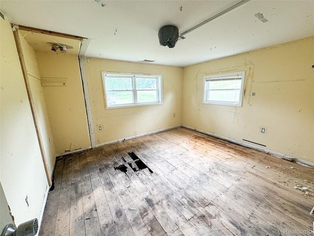 7889 Chilson Rd, Hamburg, MI 48169 - unfurnished bedroom featuring hardwood / wood-style flooring and multiple windows