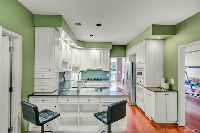 584 Cambridge Way, Bloomfield Hills, MI 48304 - kitchen featuring dark countertops, a peninsula, white cabinets, a breakfast bar, and recessed lighting