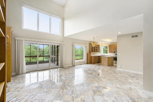 436 Pine Brae St, Ann Arbor, MI 48105 - unfurnished living room featuring light marble finish flooring, a chandelier, and a towering ceiling