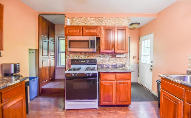 500 W Chicago St, Coldwater, MI 49036 - kitchen with range with gas stovetop, stainless steel microwave, dark wood-style floors, tasteful backsplash, and brown cabinetry