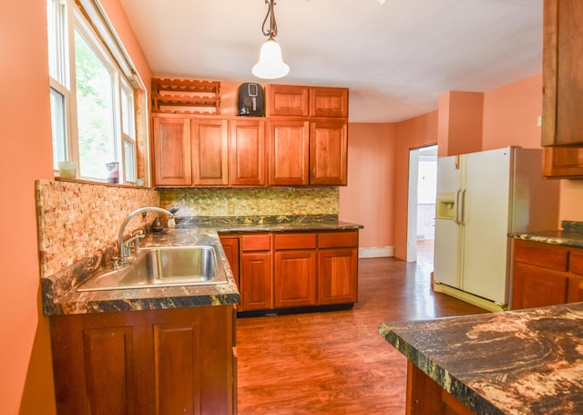 500 W Chicago St, Coldwater, MI 49036 - kitchen featuring white refrigerator with ice dispenser, wood finished floors, decorative backsplash, dark countertops, and brown cabinetry