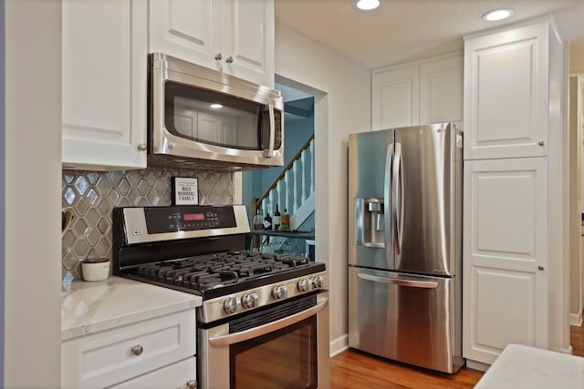 516 Zehnder Dr, Frankenmuth, MI 48734 - kitchen with stainless steel appliances, backsplash, white cabinetry, light stone countertops, and recessed lighting