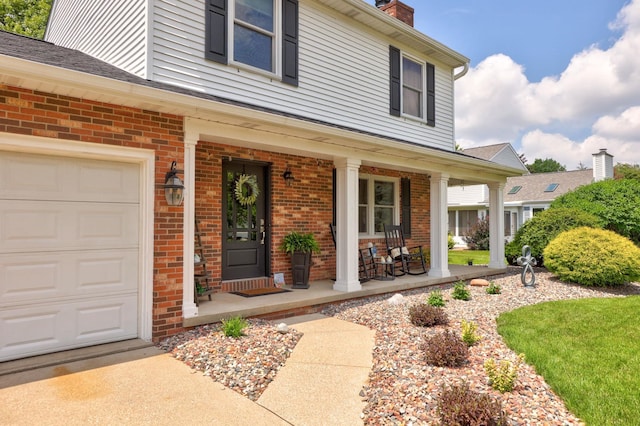 516 Zehnder Dr, Frankenmuth, MI 48734 - view of exterior entry with covered porch, brick siding, a chimney, and an attached garage