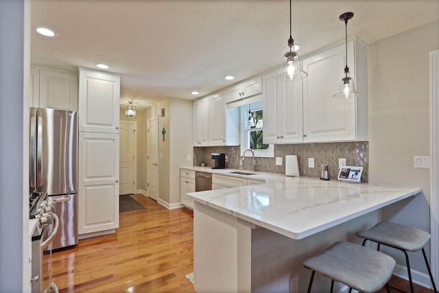 516 Zehnder Dr, Frankenmuth, MI 48734 - kitchen with stainless steel appliances, a breakfast bar, light wood-type flooring, white cabinetry, and tasteful backsplash