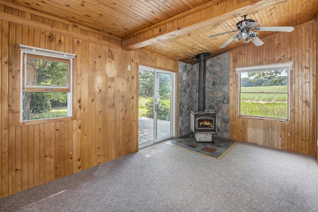 7035 W Filmore Rd, Mears, MI 49436 - unfurnished living room featuring a wood stove, plenty of natural light, carpet floors, a ceiling fan, and wood ceiling