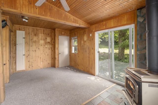 7035 W Filmore Rd, Mears, MI 49436 - carpeted empty room featuring a wood stove, wooden walls, wood ceiling, and ceiling fan