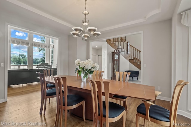 519 Hawksmoore Dr, Clarkston, MI 48348 - dining room featuring a chandelier, stairs, wood finished floors, and a tray ceiling