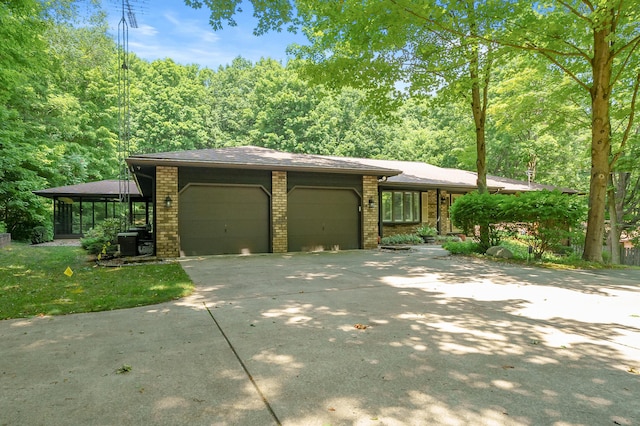 1130 W G Ave, Kalamazoo, MI 49009 - view of front of home featuring an attached garage, brick siding, concrete driveway, and a view of trees