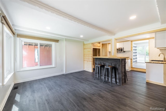 8614 Lake Rd, Grosse Ile, MI 48138 - kitchen with stainless steel microwave, dark wood-style floors, tasteful backsplash, a breakfast bar, and recessed lighting