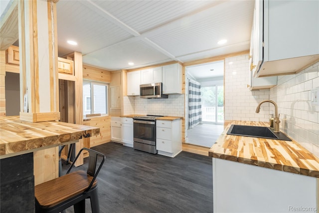 8614 Lake Rd, Grosse Ile, MI 48138 - kitchen featuring wood counters, appliances with stainless steel finishes, backsplash, dark wood-style floors, and white cabinets