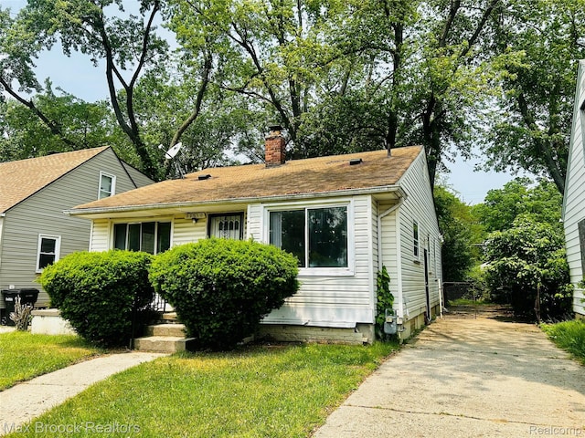 22510 Frisbee St, Detroit, MI 48219 - view of front facade featuring a chimney, a front lawn, and concrete driveway