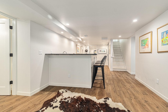 2659 Bedford Rd, Ann Arbor, MI 48104 - kitchen featuring a breakfast bar, recessed lighting, light wood finished floors, dark countertops, and a peninsula
