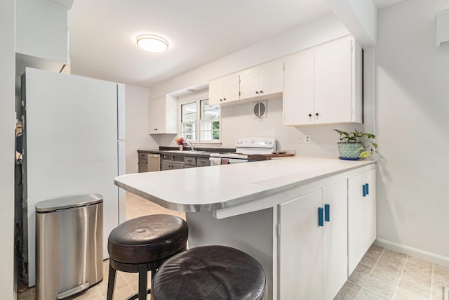 2659 Bedford Rd, Ann Arbor, MI 48104 - kitchen with white appliances, a peninsula, a breakfast bar area, white cabinetry, and light countertops