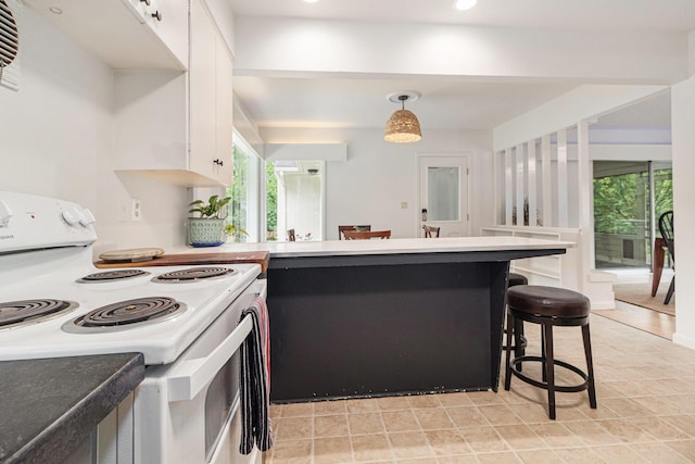 2659 Bedford Rd, Ann Arbor, MI 48104 - kitchen featuring electric range, a peninsula, white cabinetry, a kitchen bar, and pendant lighting