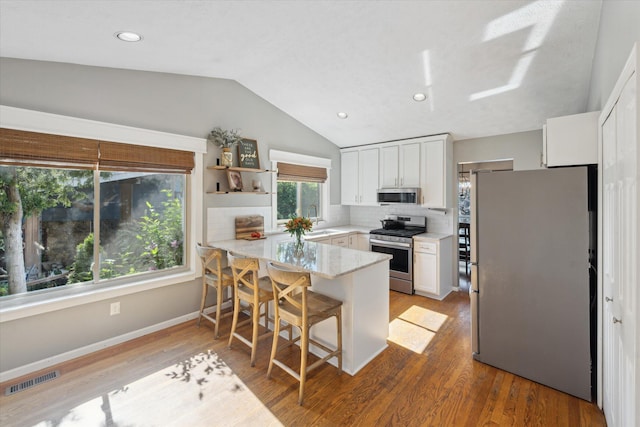 1393 Shankin Dr, Walled Lake, MI 48390 - kitchen featuring stainless steel appliances, a peninsula, white cabinets, decorative backsplash, and lofted ceiling