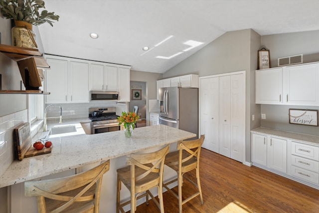 1393 Shankin Dr, Walled Lake, MI 48390 - kitchen with appliances with stainless steel finishes, tasteful backsplash, lofted ceiling, a peninsula, and wood finished floors