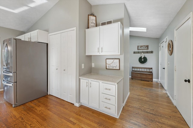 1393 Shankin Dr, Walled Lake, MI 48390 - kitchen with freestanding refrigerator, vaulted ceiling, wood finished floors, white cabinets, and light stone counters