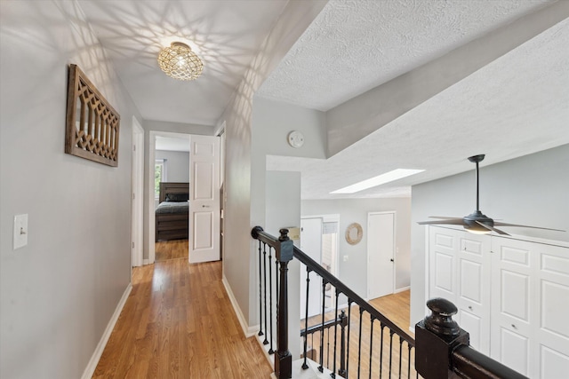 1393 Shankin Dr, Walled Lake, MI 48390 - hallway featuring light wood finished floors, an upstairs landing, and a textured ceiling