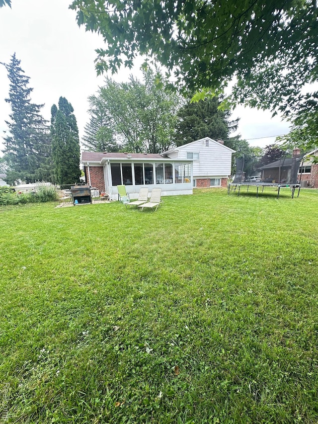 5076 Spring Well Ln, Grand Blanc, MI 48439 - rear view of property featuring a trampoline, a sunroom, and a yard