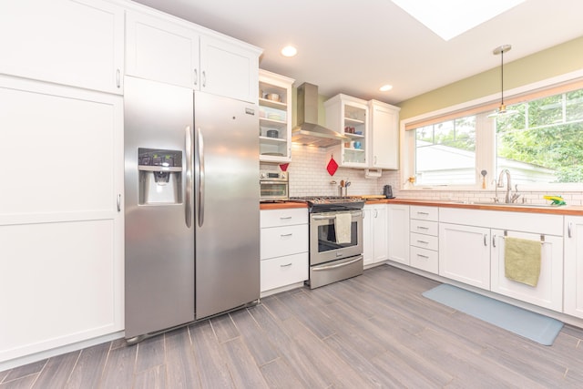 2100 Alice St, Ann Arbor, MI 48103 - kitchen with appliances with stainless steel finishes, wall chimney exhaust hood, wooden counters, tasteful backsplash, and white cabinets