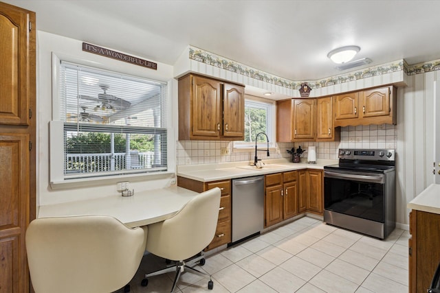 11 Geiger Ave, Battle Creek, MI 49037 - kitchen with appliances with stainless steel finishes, tasteful backsplash, brown cabinets, light countertops, and light tile patterned floors