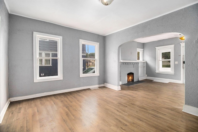 1850 S Burdick St, Kalamazoo, MI 49001 - unfurnished living room featuring wood finished floors, arched walkways, a fireplace, ornamental molding, and a textured wall