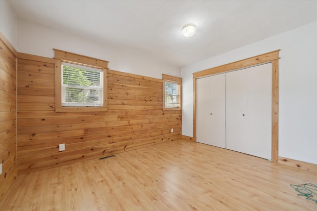 222 E Mill St, Hastings, MI 49058 - unfurnished bedroom with light wood-style flooring, a closet, and wood walls