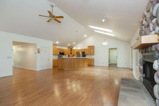1803 Bell Rd, Niles, MI 49120 - unfurnished living room featuring a skylight, ceiling fan, high vaulted ceiling, a fireplace, and light wood-style flooring