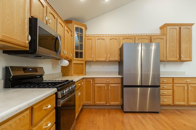 1803 Bell Rd, Niles, MI 49120 - kitchen featuring stainless steel appliances, light countertops, light wood finished floors, lofted ceiling, and glass insert cabinets