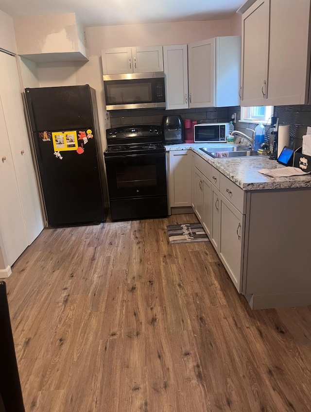 2032 Daron Pl, Flint, MI 48505 - kitchen with black appliances, light wood-style flooring, decorative backsplash, and light stone countertops
