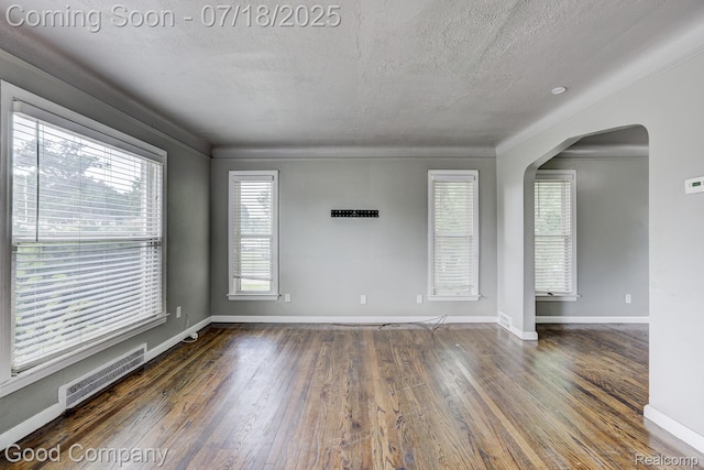 21797 Moross Rd, Grosse Pointe, MI 48236 - spare room with arched walkways, a textured ceiling, plenty of natural light, and hardwood / wood-style flooring