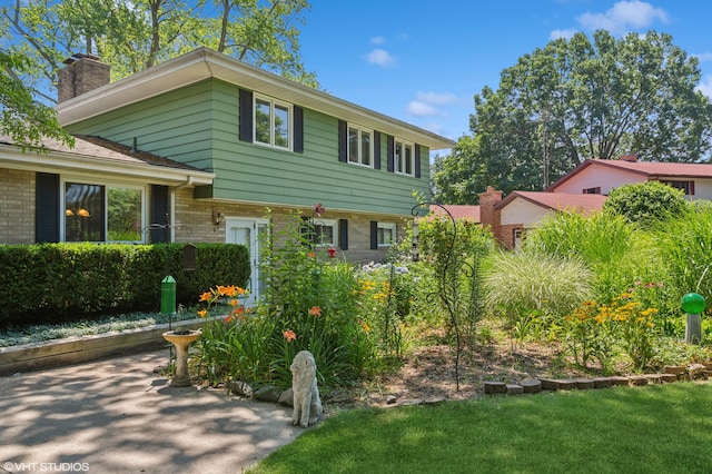 1320 S Manor Dr, Saint Joseph, MI 49085 - tri-level home featuring a chimney, brick siding, and a front lawn