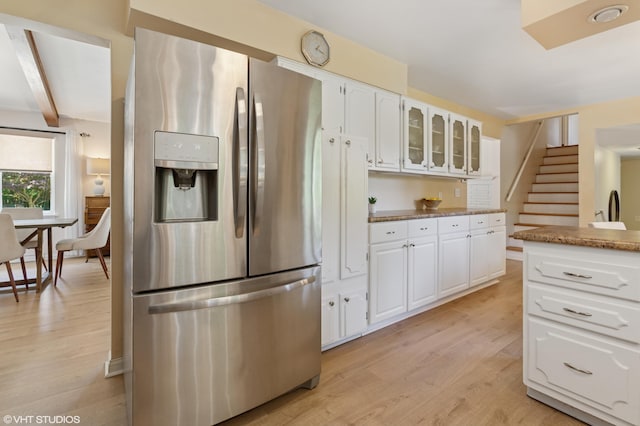 1320 S Manor Dr, Saint Joseph, MI 49085 - kitchen featuring stainless steel refrigerator with ice dispenser, light wood-style flooring, glass insert cabinets, and white cabinetry