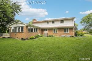 402 Thomas Ln, Grand Blanc, MI 48439 - rear view of property featuring a yard, brick siding, and a chimney