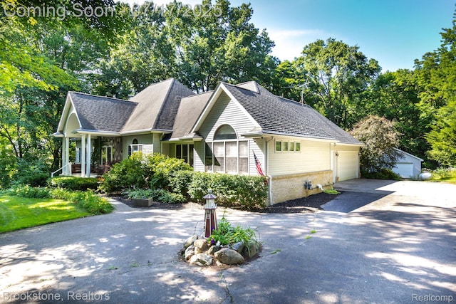 8808 Big Lake Rd, Clarkston, MI 48346 - view of front of house featuring brick siding, driveway, view of scattered trees, and an outbuilding
