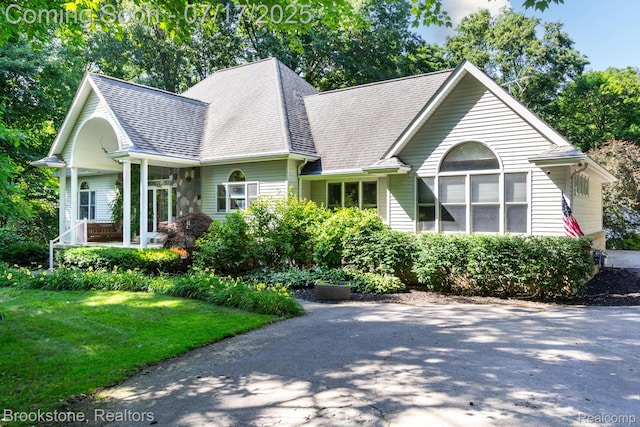 8808 Big Lake Rd, Clarkston, MI 48346 - view of front facade featuring a shingled roof, a front lawn, and covered porch