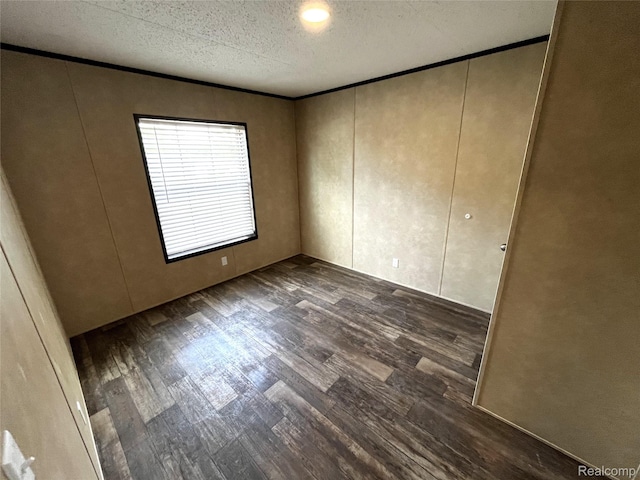 8499 LOT214 E M 71, Durand, MI 48429 - spare room featuring dark wood finished floors, a decorative wall, crown molding, and a textured ceiling