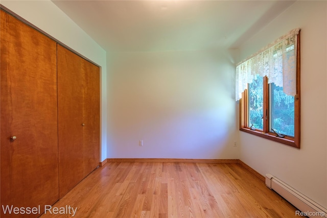 2465 Texter Rd, Leonard, MI 48367 - unfurnished bedroom featuring a baseboard radiator, a closet, and light wood-style flooring