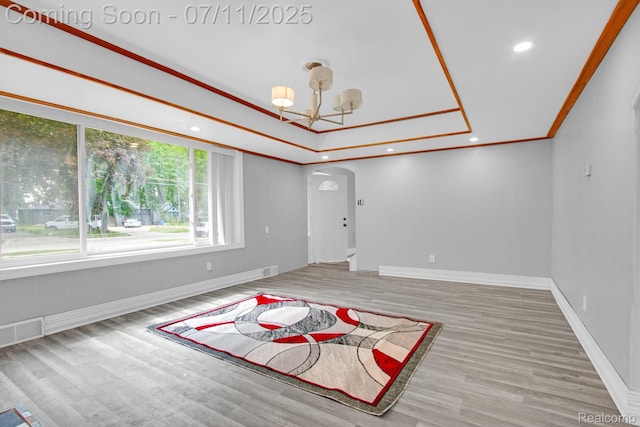 24370 Eureka Ave, Warren, MI 48091 - empty room featuring arched walkways, a chandelier, a raised ceiling, wood finished floors, and crown molding