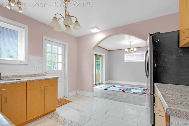 24370 Eureka Ave, Warren, MI 48091 - kitchen featuring a chandelier, freestanding refrigerator, light marble finish flooring, and arched walkways