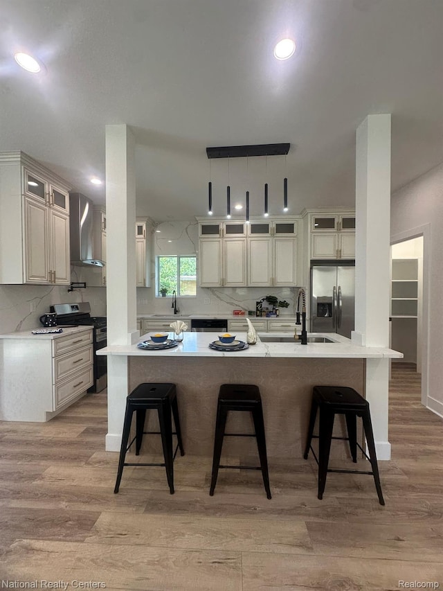 1666 Albany St, Ferndale, MI 48220 - kitchen with wall chimney exhaust hood, stainless steel appliances, a breakfast bar, decorative backsplash, and recessed lighting