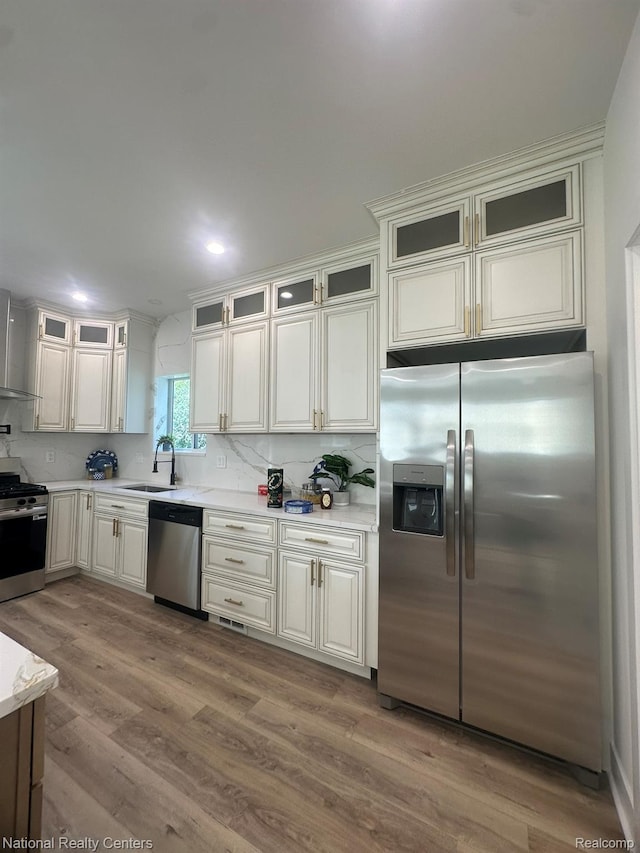 1666 Albany St, Ferndale, MI 48220 - kitchen featuring appliances with stainless steel finishes, light countertops, glass insert cabinets, wood finished floors, and decorative backsplash