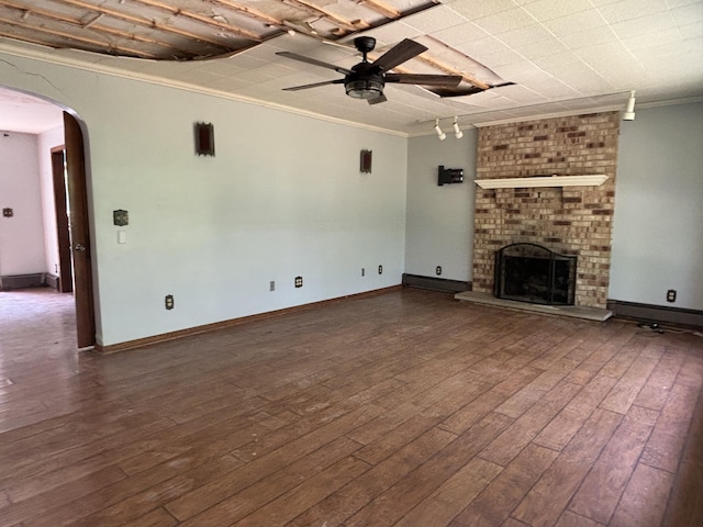 135 S Steer St, Addison, MI 49220 - unfurnished living room featuring crown molding, arched walkways, a ceiling fan, wood finished floors, and a brick fireplace