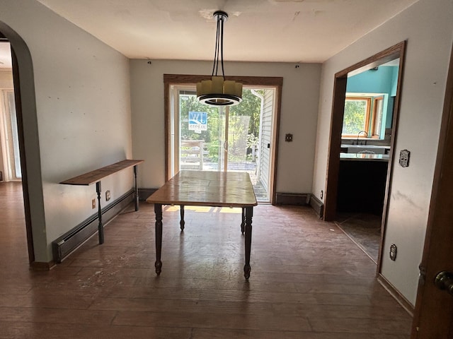 135 S Steer St, Addison, MI 49220 - unfurnished dining area featuring baseboard heating, arched walkways, and hardwood / wood-style floors