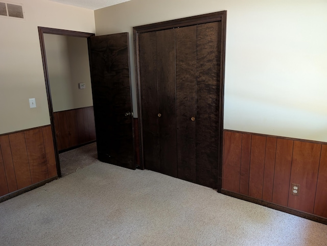 287-289 S Waverly Rd, Holland, MI 49423 - unfurnished bedroom with a wainscoted wall, a closet, wooden walls, and carpet
