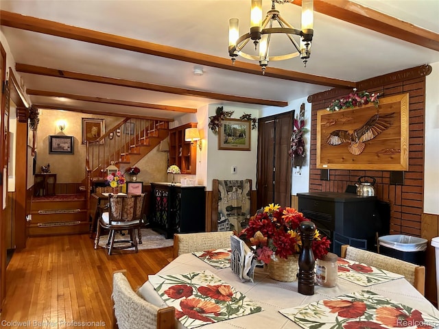 7351 Chain Lake Dr, South Branch, MI 48761 - dining room with a chandelier, hardwood / wood-style flooring, beam ceiling, stairs, and a wood stove